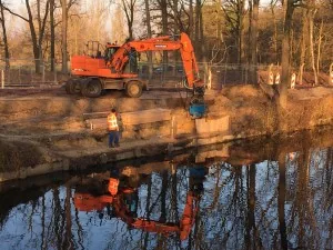 Oranje graafmachine bij een sloot